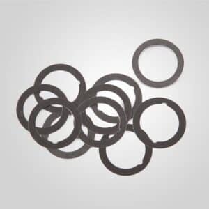 Pile of black metal washers on gray background.
